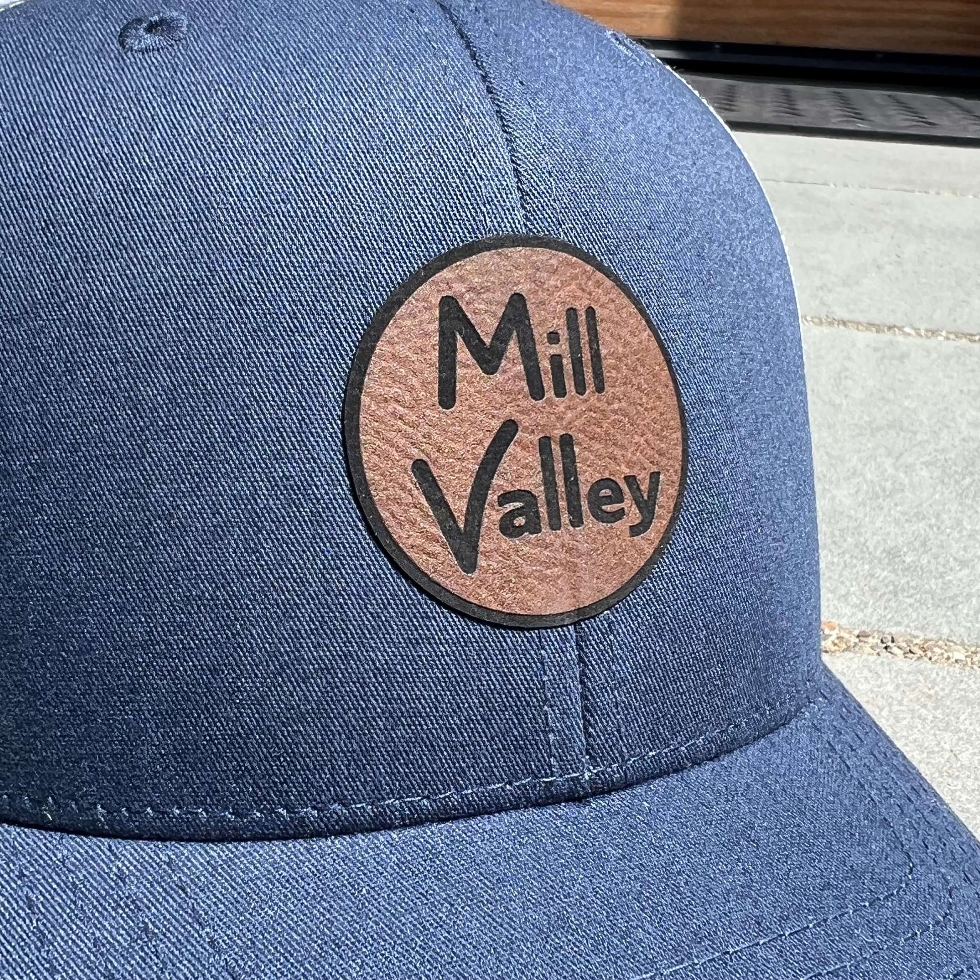 Lowkey Local navy blue structured trucker hat with a circular Mill Valley leather patch on the front panel
