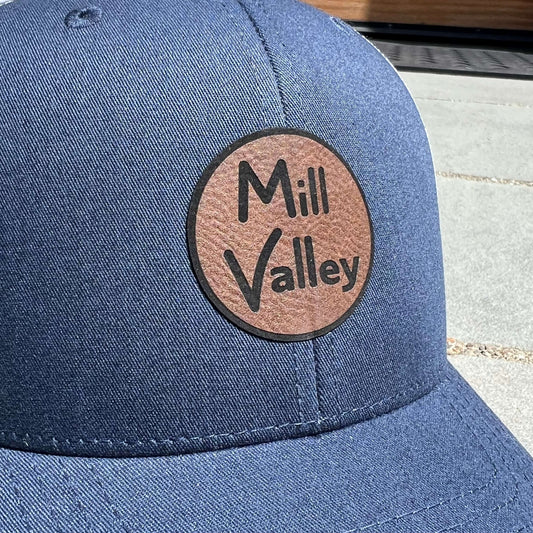 Lowkey Local navy blue structured trucker hat with a circular Mill Valley leather patch on the front panel