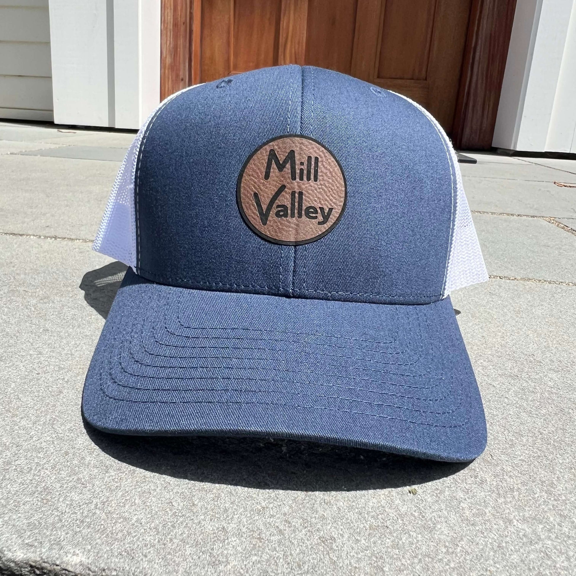 Lowkey Local navy blue trucker hat with white mesh back and circular Mill Valley leather patch on front